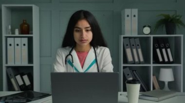 Sıkılmış genç kadın doktor. Stajyer doktor. Dizüstü bilgisayarda çalışıyor. Hastaları kontrol ediyor.