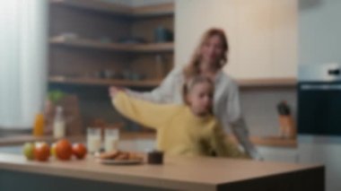 Bulanık aile manzarası anne ve küçük kızı mutfakta eğlenceli dansların keyfini çıkarıyorlar. Anne kadın bebek bakıcısı, evde müzik eşliğinde el ele dans eden ergen çocuk kızıyla eğleniyor.