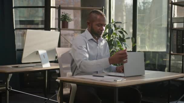 リラックスしたアフリカ系アメリカ人の成熟したビジネスマンのシニア幸せな男は 晴れた暖かい快適なオフィスでリラックスしたコンピュータの仕事を終了します 男性専門家ストレッチ筋肉頭の後ろに手を置く一日の終わり — ストック動画