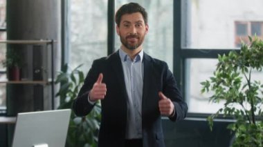 Ofiste duran Kafkasyalı iş adamı mutlu beyaz adam iş ilerlemesinden memnun olmuş jest onayı gösteriyor. Şirket çalışanı, iyi sonuç alkışı göstererek işlerinde başarılı olduğunu gösteriyor.