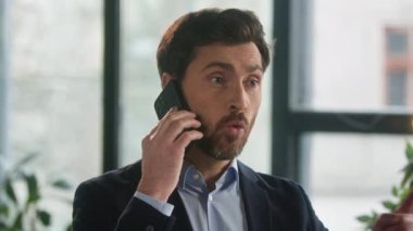Close-up frustrated businessman aggressive loud talk on phone in office angry nervous man leader CEO discuss business problems on cellphone feel stress annoyed male has conflict speaking on smartphone