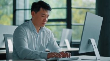 Portre odaklı erkek ofis çalışanı web tasarımcısı Asyalı orta yaşlı iş adamı iş yerinde oturuyor masaüstü bilgisayar geliştirme teknolojisi programını kullanıyor çevrimiçi ticaret piyasası dijital verilerini analiz ediyor