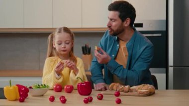 Mutfakta beyaz bir aile var. Yetişkin bir baba ve evlatlık bir kız çocuğu akşam yemeği masasında oturmuş kahvaltıda gevrek baget yiyorlar ve birlikte evde yemeğin tadını çıkarıyorlar.