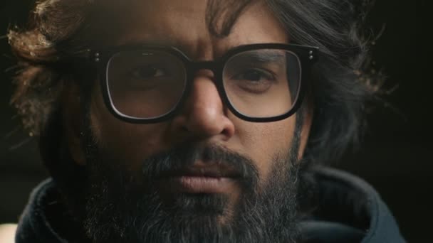 頭のショットの肖像画極端なクローズアップ男性の顔は暗い背景でカメラを見てメガネでインドの30万人のビジネスマンひげを生やした アラビア人のまじめなビジネスマン眼鏡をかけて見て — ストック動画