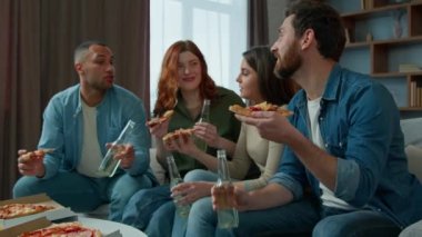 Etnik arkadaşlar, takım arkadaşları evde pizza yiyorlar, çok ırklı erkekler, kadınlar kanepede oturup bira içiyorlar, lezzetli yemekler yiyorlar, çeşitli yemekler yiyorlar, çeşitli insanlar hafta sonları atıştırmalık ve içeceklerle dinleniyorlar.