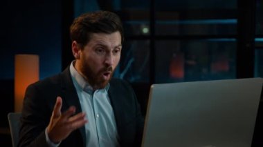 Annoyed angry businessman Caucasian middle-aged 40s man CEO employee mad furious crazy shouting fail online business project on computer trouble failure problem stress evening night office background