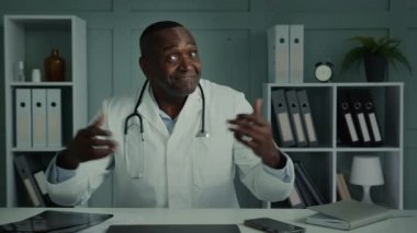 Doktor Man, yaşlı Afro-Amerikan tıp uzmanı hasta ile sanal toplantı arasında mesafeli konuşuyor. Web kamerası konferansı uygulaması kullanıyor. Omuzlarını silkeliyor.
