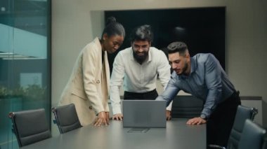 Çok ırklı iş adamları, dizüstü bilgisayarlı çeşitli meslektaşlarıyla el ele tutuşup tezahürat yaparak online başarılarını kutluyor. Başarılı takım avuç içlerini birbiri ardına yığarak başarıyı kutluyor.