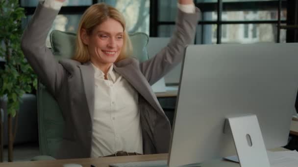 笑顔40代のビジネス女性は 現代のオフィスの机に座ってストレッチコンピュータの仕事を終えた オンライン仕事の後に満足して幸せなリラックスした中年のビジネスマンの女性頭の後ろに手を置く — ストック動画