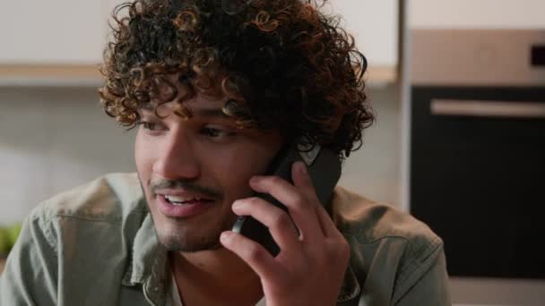 Χαρούμενος Ινδός Νεαρός Άνδρας Σγουρά Μαλλιά Μιλάει Τηλέφωνο Στην Κουζίνα — Αρχείο Βίντεο