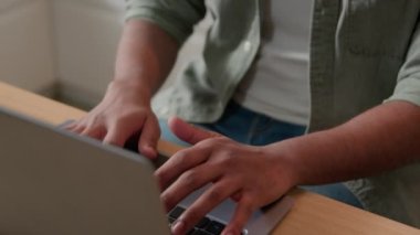 Klavyesini dizüstü bilgisayarda yazan erkek oyuncu mutfaktaki masada çalışan Hintli iş adamı bilgisayar mesafesinde çalışan serbest çalışan Arap bir adama gülümsüyor. Erkek öğrenci evde okuyor.