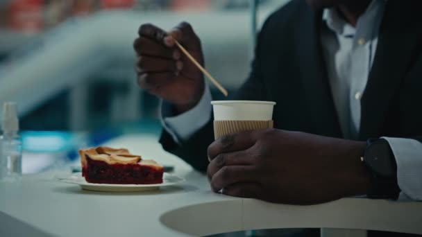 閉じますクロップビュー認識できないアフリカのカフェ訪問者未知の男ビジネスマンで正式なスーツでテーブルでカフェテリアケーキの攪拌ミックス砂糖でコーヒーティーラテカプチーノと木製スティック — ストック動画