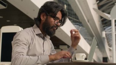 Düşünceli Hintli işadamı bilgisayarla uzaktan kumandayla yazarak internet üzerinde çalışıyor konsantre Arap adam yöneticisi dijital verileri analiz ediyor kapalı mekanlarda bilgisayar uygulaması kullanarak iş planı yaratıyor sosyal ağda e-posta gönderiyor