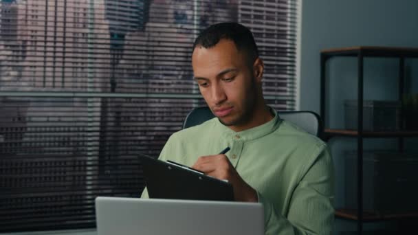 Afrykański Amerykański Menedżer Człowiek Patrząc Ekranie Laptopa Pisząc Raport Finansowy — Wideo stockowe