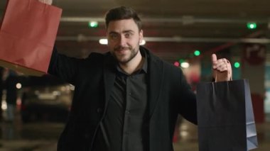 Alışveriş torbalı beyaz bir adam moda mağazasından hediye alıyor. Müşteri müşterisi, kırmızı ya da mavi alışverişleri seçiyor. Park yerinde paket tutan yetişkin bir işadamı.