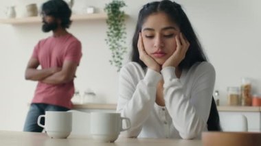 Mutfakta kocasıyla tartıştıktan sonra ilişki sorunlarını düşünen Hintli bir kadın, arka planda bir erkeği gücendirdi. Farklı etnik çeşitlilikteki evli çiftler anlaşmazlıkları tartışıyorlar.