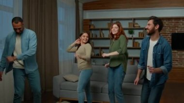 Yeni evdeki taşınma gününü kutlayan çeşitli arkadaşlar ev partisinde toplandı. Çok ırklı grup dansçıları oturma odasında eğleniyor erkekler dans ediyor kadınlar dans ediyor müzik eşliğinde dans ediyorlar.