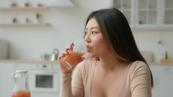 韩国女人喝新鲜的冰沙橙汁 亚洲素食主义者女孩在厨房里品尝一杯维生素果香蜜桃 喝健康饮食减肥保健品早晨排毒 — 图库视频影像