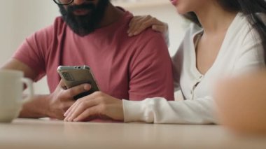Kesilmiş manzara tanınmayan kadın ve erkek akıllı telefon kullanarak yemek masasında oturuyor birlikte internet siparişi veriyorlar evli çiftler cep telefonlarıyla internet üzerinden alışveriş yapıyorlar.