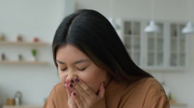 Sağlıksız, hasta, Asyalı, hapşırık suratlı, mutfakta elleri olan Japon bir iş kadınının burnu akıyor. Kovid-19 semptomlarına karşı alerjisi var. Koreli kadın evde hapşırırken kötü hissediyor.