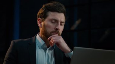 Düşünceli, düşünceli, orta yaşlı, Kafkasyalı, 40 'lı yaşlarda bir işadamı laptop işi ile ilgili yeni bir fikir planlama projesi düşünüyor.