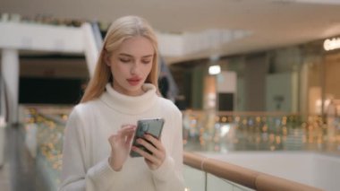Kafkasyalı müşteri alışveriş merkezinde akıllı telefonuyla modern iş merkezindeki giyim mağazasına gidiyor. 20 'li yaşlarda kadın alışverişçi kız internete girip cep telefonu uygulamaları kullanarak internetten sipariş veriyor.