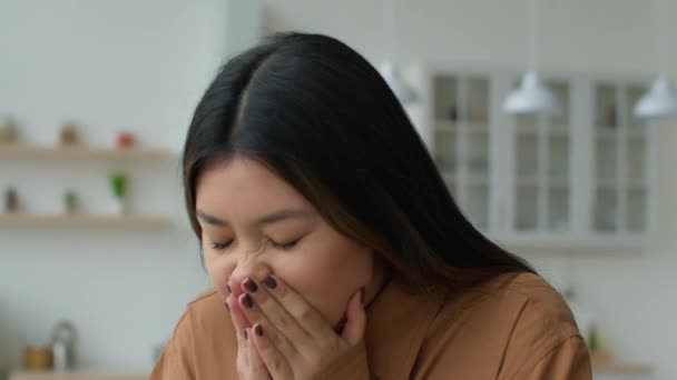 不健全なアジアの女の子のくしゃみカバー顔で手でキッチン日本のビジネス女性苦しむ鼻水持っていますアレルギーCovid 19症状熱インフルエンザ韓国人女性感じ悪いくしゃみ寒さに家 — ストック動画