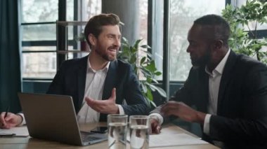İki mutlu, çok ırklı adam toplantı odasında laptopla gülen iş adamları Kafkasyalı yönetici yönetici Afrikalı Amerikalı işçi ile birlikte çalışıyorlar.
