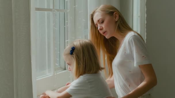 Biała Matka Małą Przedszkolanką Stojąca Porannym Świetle Patrząca Przez Okno — Wideo stockowe