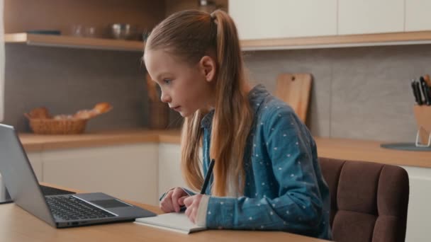 可爱的小学白人女学生在厨房用笔记本电脑学习 小女儿 小女生做家庭作业 写作业 远程学习 儿童家庭教育电子学习检疫 — 图库视频影像