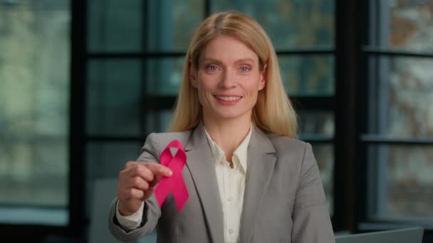 肖像画笑顔白人の中年女性は Hivエイズ啓発疾患予防サインボランティアチャリティシンボルと現代のオフィスビジネス女性にポーズをとる赤いリボンを保持しています 世界乳がんの日 — ストック動画