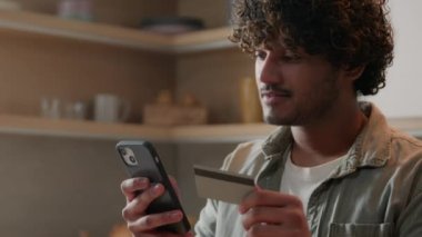 Kredi kartı mobil bankacılık uygulaması olan Hintli erkek Arap müşterisi. İnternetten ödeme yapıyor. Yemek siparişi alıyor, alışveriş hizmetleri alıyor.