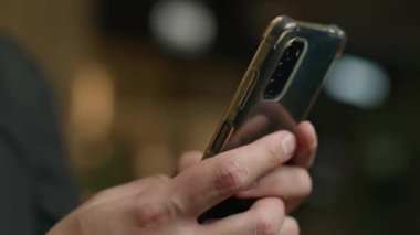 Yakın çekim erkek elleri cep telefonuyla sohbet ediyor. Cep telefonunda dokunmatik mesaj yazıyor. Tanımlanamayan iş adamı akıllı telefon mesajı atıyor.