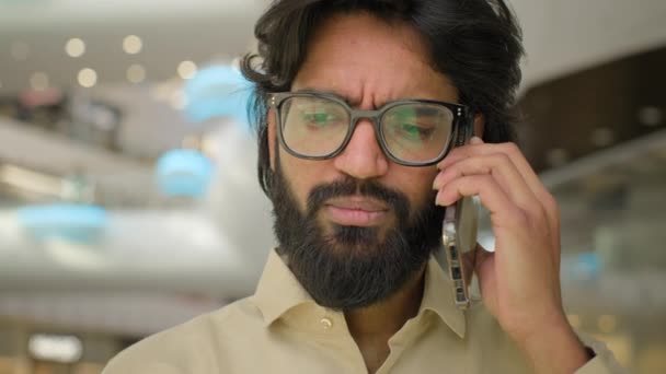 オフィスでの肖像アラビア人男性の眼鏡電話でビジネスコールに応答します 深刻なインドの男性ビジネスマンの経営者の起業家を閉じます遠隔コミュニケーショントークモバイル会話 — ストック動画