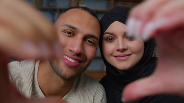 多种族夫妇非洲裔美国男人笑着穆斯林女人头戴头巾通过连指心形联合手框框情人节浪漫的爱妻丈夫的爱情 — 图库视频影像