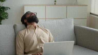 Evde dizüstü bilgisayarla çalışmaktan yorgun düşmüş yorgun Arap Müslüman adam koltukta uyuyakalıyor yorgun Hintli iş adamı kanepeye uzanıyor yorgunluk yorgunluğu, dinlenmeye ihtiyacı var dinlenmeye