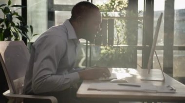 Şaşırtıcı etnik Afrikalı Amerikalı yetişkin iş adamı güneşli ofis ışıklarıyla kazandı. Mutlu duygusal adam zafere seviniyor. Şanslı galibiyet online iş projesi bilgisayarda başarıyı kutluyor.