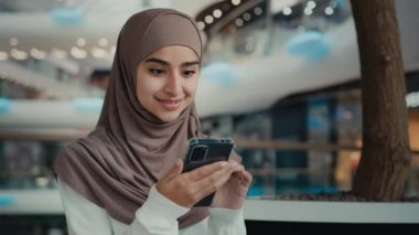 tesettürlü Arap müslüman bayan öğrenci cep telefonu ekranı alışverişine bakın dijital uygulama kullanın internet indirimi kazanın gülümseyen iş kadını müşteri alışverişi yapın e-ticaret yapın