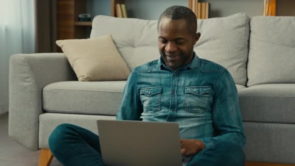 Uśmiechnięty Afroamerykanin Piszący Laptopie Przeglądający Portale Społecznościowe Przytulnym Salonie Biznesmen — Wideo stockowe