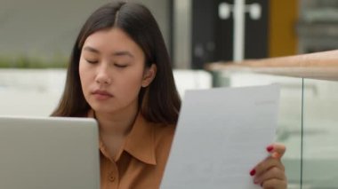 Kafe alışveriş merkezindeki gazetelerle çalışan Asyalı iş kadını Çinli kadın kredi faturası belgesi okudu Japon serbest muhasebeci kız muhasebeci dizüstü bilgisayar sayısının finansmanından kredi vergisi ödedi