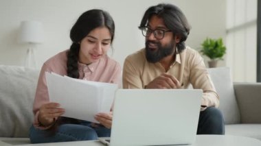 Arap çift ev sahipleri ev kirası belgelerini okuyorlar ev kiralarını internet üzerinden ödüyorlar çok ırklı kadın ve erkek bütçesi hakkında konuşuyorlar kredi ödemeleri banka ipoteği hakkında konuşuyorlar