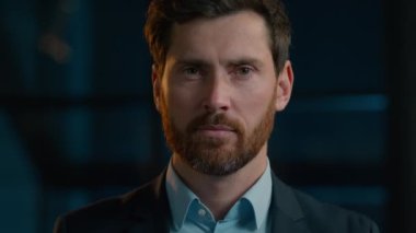 Yakın plan, beyaz, orta yaşlı, sakallı, iş adamı yönetici CEO 'su. Gece ofis portresi. Takım elbiseli, dişçi kılıklı, gülümseyen, dişlek gülümseyen bir erkek.