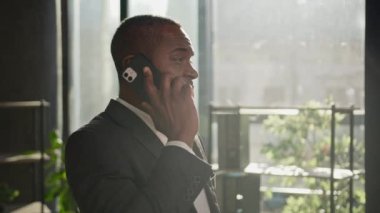 Olgun, mutlu girişimci, etnik Afrikalı, Amerikalı, kıdemli iş adamı. Güneş ışınları altında cep telefonu standı. Uzak iş yerleri.