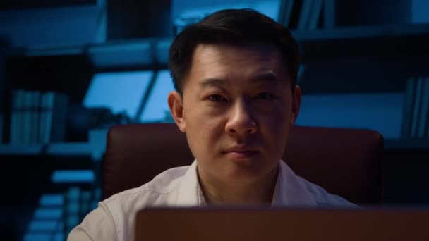 幸せなアジア系韓国人ビジネスマンが夜にオフィスでインターネットで働くノートパソコンを入力大人気楽な中国人男性リーダー日本人男性マネージャー笑顔でおもちゃの笑顔でカメラで職場の肖像画 — ストック動画