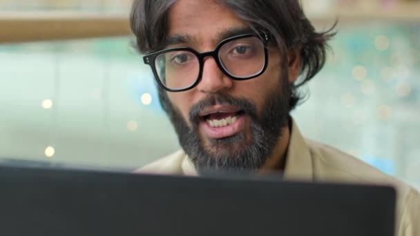 近视印度快乐商人戴眼镜留胡子的工人阿拉伯人对着手提电脑交谈网络摄像头商务会议视频呼叫在线咨询遥远的谈判在办公室进行虚拟交谈 — 图库视频影像