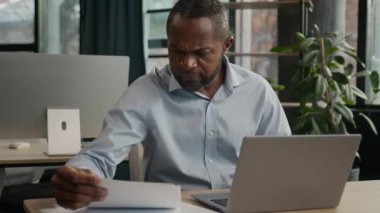 Depresyondaki Afrikalı Amerikalı, yetişkin iş adamı. Dizüstü bilgisayarlı, stresli hasta adam. Gazeteleri okuyor.