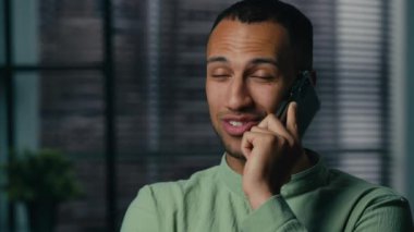 Gülümseyen Afrikalı Amerikalı adam cep telefonuyla konuşuyor. Etnik Latin iş adamı, girişimci danışman. Ofisteki iş görüşmelerine cep telefonuyla cevap veriyor.