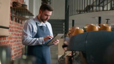 Kafkasyalı garson garson kafe sahibi iş adamı dijital tablet kullanarak apron kumandalı erkek restoran çalışanı kafeterya tezgahının arkasında çevrimiçi sipariş veriyor.
