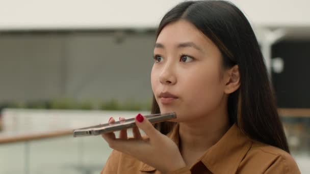 アジア系中国人女性スピーカーフォンで録音音声音声メッセージボイスメールモバイルマイクトークスピーカー韓国人女の子ビジネス女性Aiスマートフォン技術で携帯電話を話して — ストック動画
