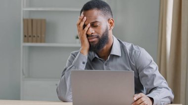 Üzücü bir şekilde, etnik sakallı ofis çalışanı iş yerinde Afrika kökenli Amerikalı iş adamı yöneticisi yönetici iş yerinde baş ağrısı şikayeti yaşıyor.